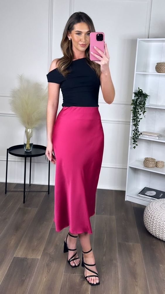 Off-shoulder black top with a high-waisted fuchsia silk skirt